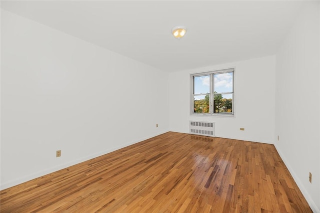 spare room featuring radiator heating unit and wood-type flooring