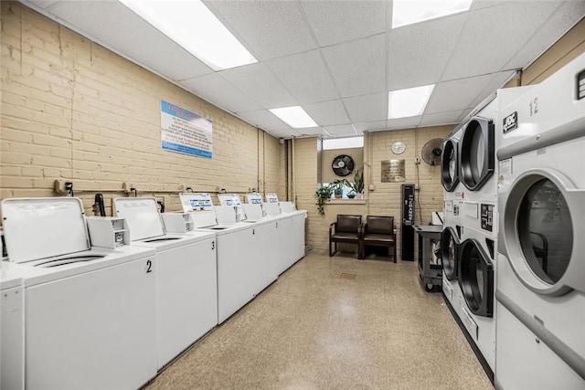 laundry area featuring stacked washer / dryer, brick wall, and separate washer and dryer