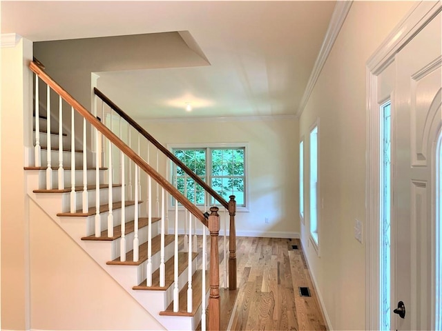 stairs with hardwood / wood-style floors and crown molding