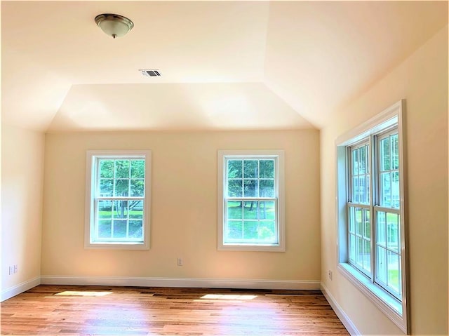 spare room featuring light hardwood / wood-style flooring and lofted ceiling