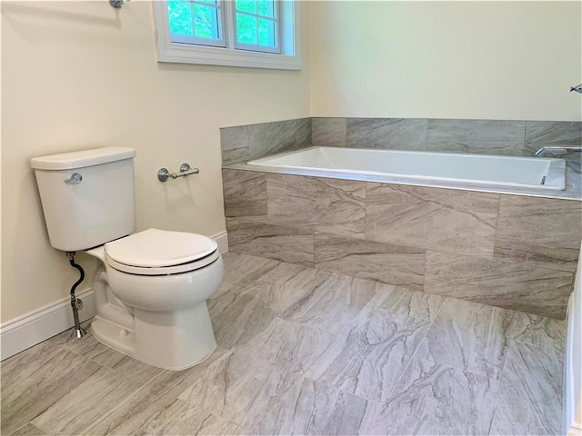 bathroom featuring a relaxing tiled tub and toilet