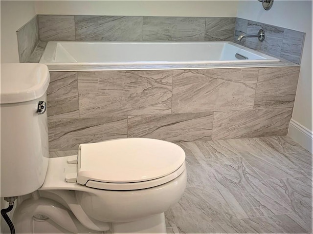 bathroom with toilet and tiled tub