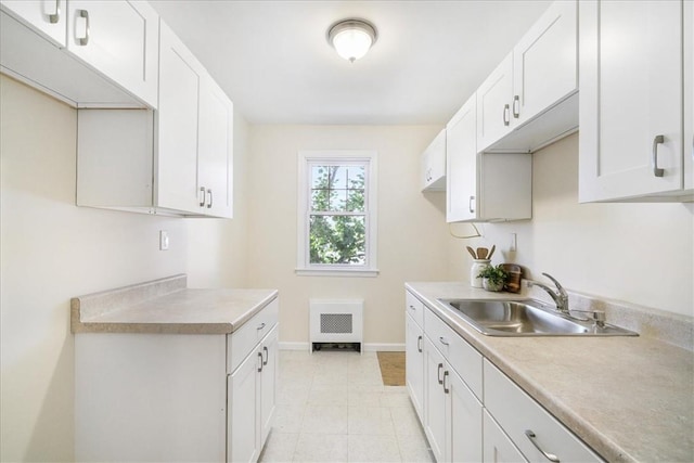 kitchen featuring white cabinetry, sink, and light tile patterned flooring