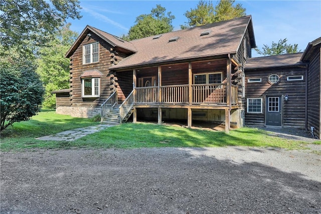 rear view of property featuring a lawn and a porch