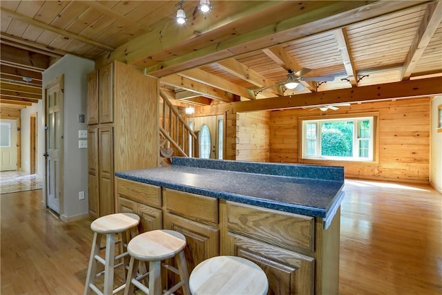 kitchen with light wood-type flooring, wooden ceiling, a kitchen island, and wooden walls