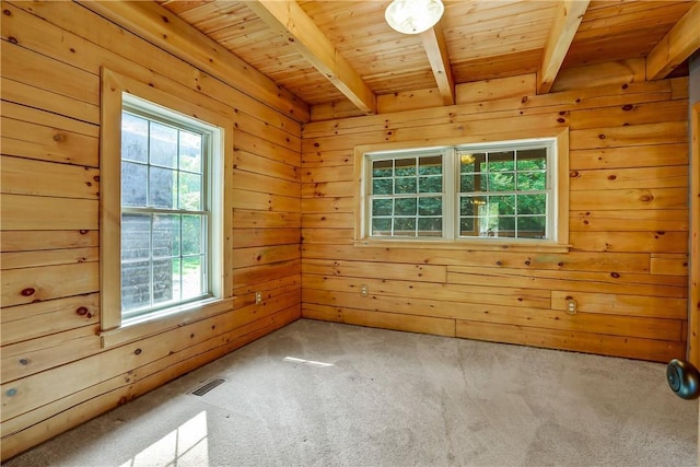 empty room with beam ceiling, carpet floors, wooden ceiling, and wood walls