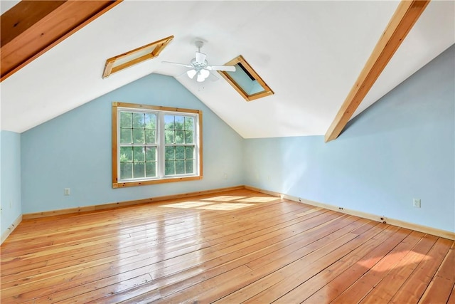 additional living space with ceiling fan, light hardwood / wood-style floors, and lofted ceiling with skylight