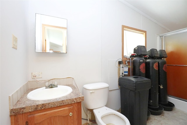 bathroom featuring vanity, toilet, a shower with door, and crown molding