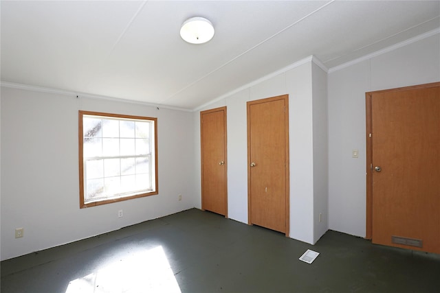 unfurnished bedroom featuring two closets, vaulted ceiling, and ornamental molding