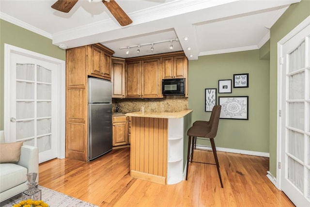 kitchen with backsplash, stainless steel fridge, light wood-type flooring, ornamental molding, and a breakfast bar area