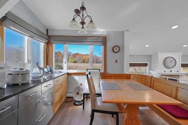 dining room with a baseboard heating unit, lofted ceiling, a notable chandelier, and hardwood / wood-style flooring