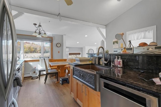 kitchen with appliances with stainless steel finishes, baseboard heating, decorative light fixtures, dark stone countertops, and light hardwood / wood-style floors