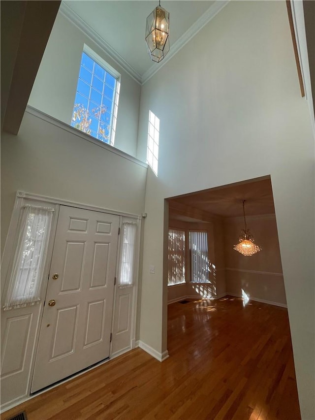 entrance foyer featuring hardwood / wood-style flooring, plenty of natural light, ornamental molding, and a notable chandelier