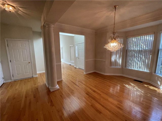 unfurnished dining area with decorative columns, a wealth of natural light, light hardwood / wood-style flooring, and a chandelier