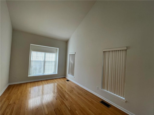 spare room with high vaulted ceiling and light hardwood / wood-style flooring