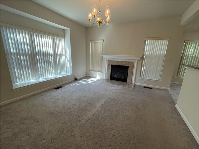 unfurnished living room with a notable chandelier, plenty of natural light, and light carpet