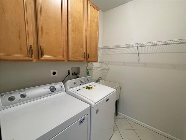 clothes washing area with separate washer and dryer, light tile patterned floors, and cabinets