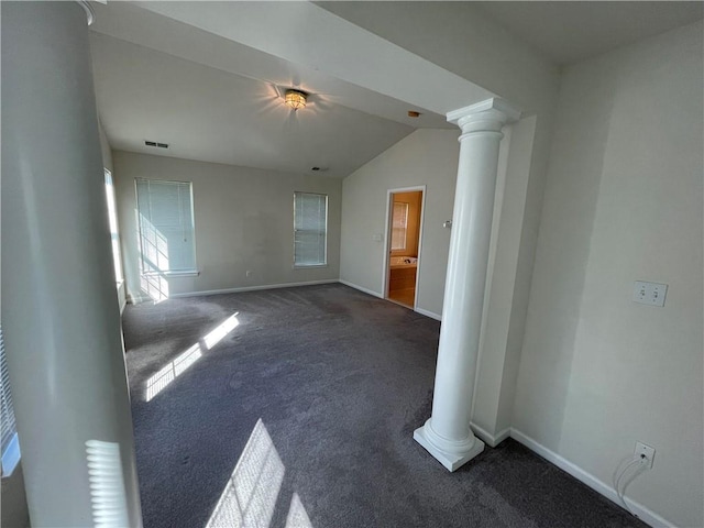 empty room featuring dark carpet, vaulted ceiling, and decorative columns