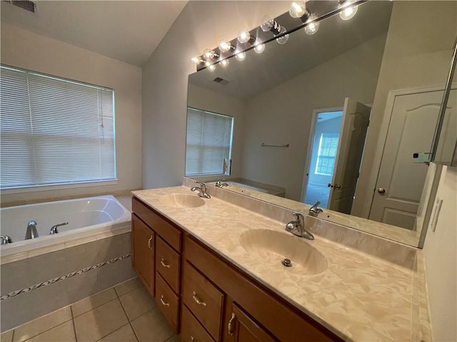 bathroom featuring tile patterned floors, vanity, tiled tub, and vaulted ceiling