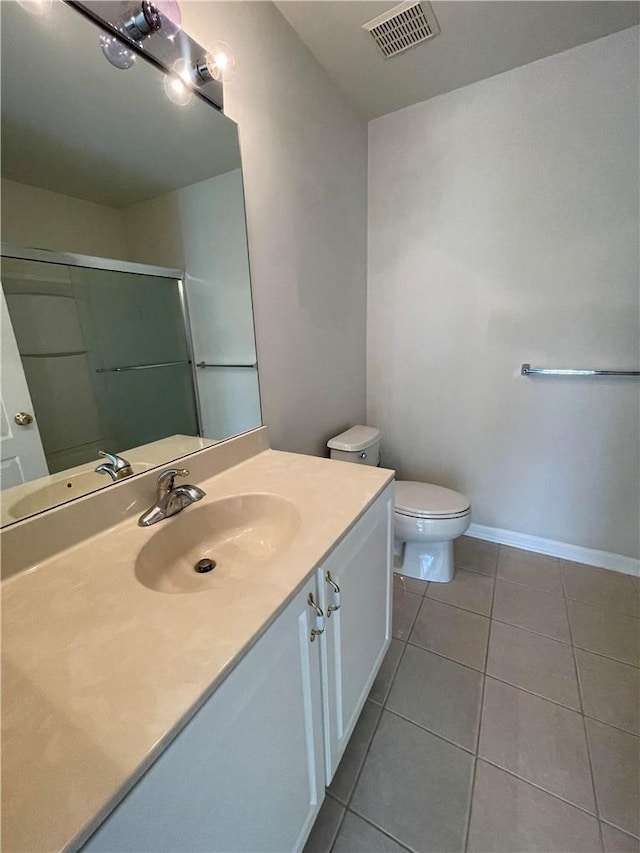 bathroom with toilet, vanity, tile patterned floors, and an enclosed shower