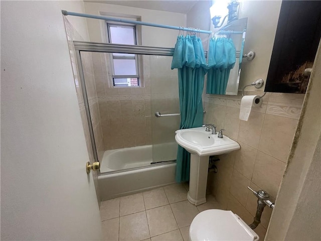 full bathroom with tile patterned floors, sink, tiled shower / bath combo, toilet, and tile walls