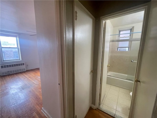 hall with radiator, a healthy amount of sunlight, and light hardwood / wood-style floors