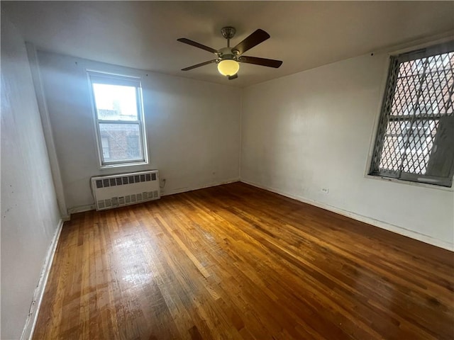 empty room featuring radiator heating unit, ceiling fan, and wood-type flooring