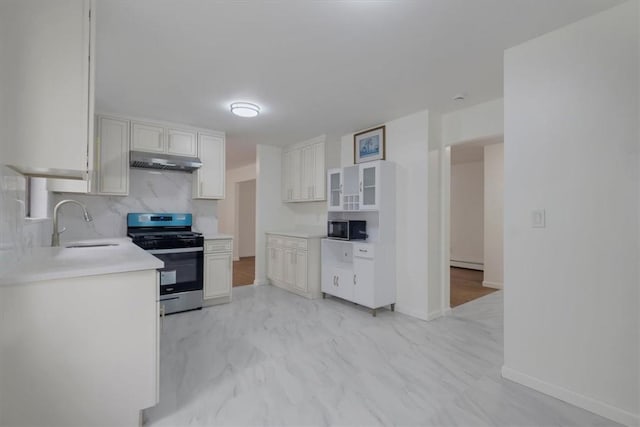 kitchen with white cabinets, backsplash, stainless steel range oven, and sink