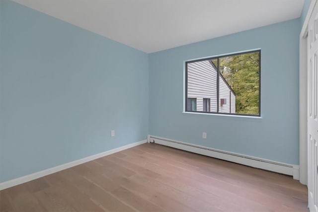 empty room with light wood-type flooring and a baseboard heating unit