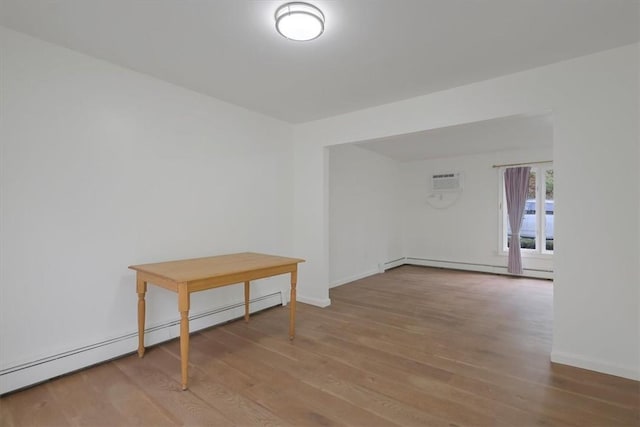 spare room with a wall mounted AC, hardwood / wood-style floors, and a baseboard radiator