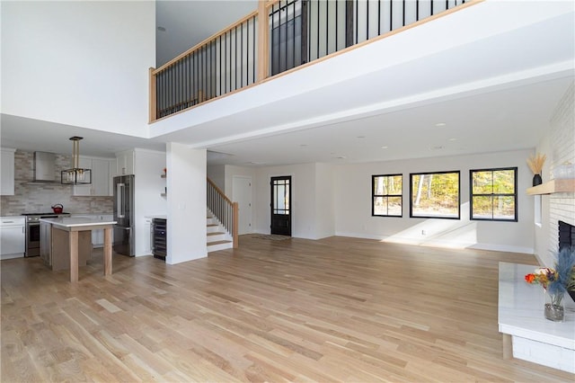 unfurnished living room with a large fireplace, beamed ceiling, a high ceiling, and light hardwood / wood-style floors