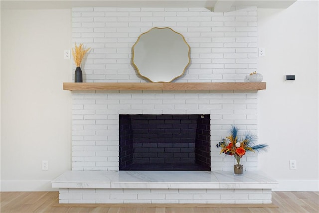 room details featuring a brick fireplace and wood-type flooring