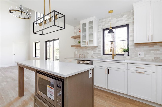 kitchen with appliances with stainless steel finishes, white cabinetry, decorative light fixtures, and sink