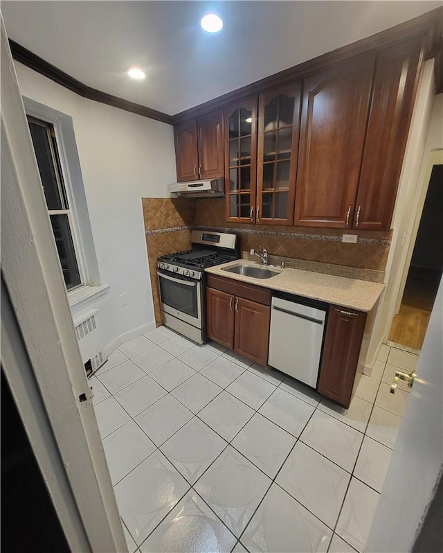 kitchen with decorative backsplash, glass insert cabinets, gas stove, under cabinet range hood, and dishwashing machine