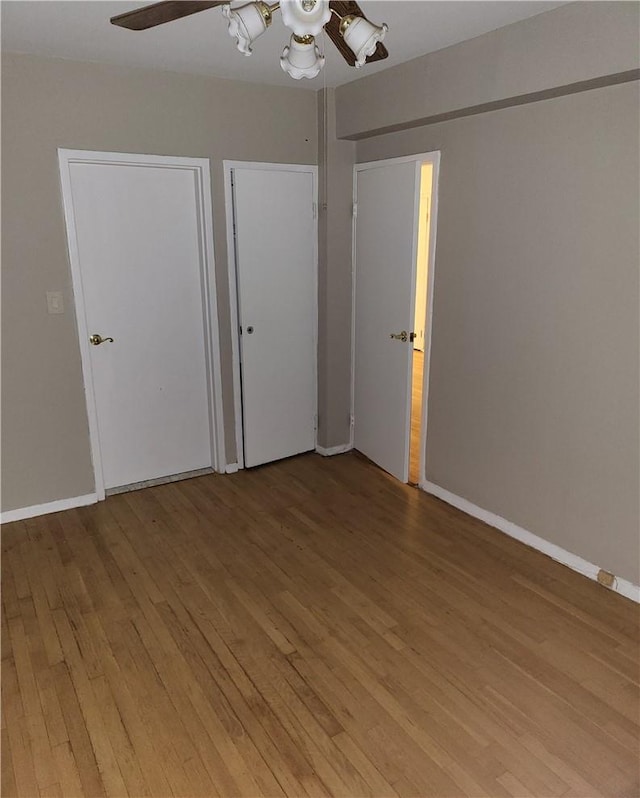 unfurnished bedroom with light wood-type flooring, a ceiling fan, and baseboards