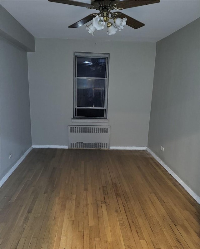 spare room with a ceiling fan, baseboards, radiator heating unit, and wood finished floors