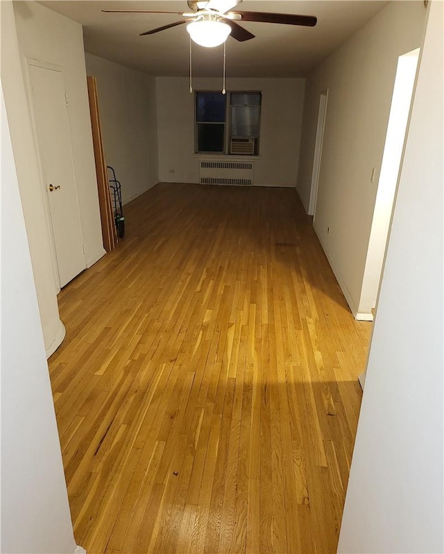 unfurnished living room featuring radiator, light wood-style floors, and ceiling fan