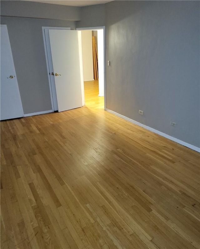 unfurnished room with light wood-type flooring and baseboards