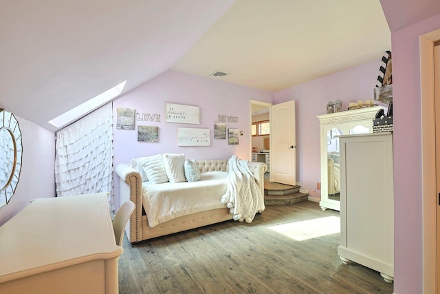 bedroom with lofted ceiling with skylight, visible vents, and wood finished floors