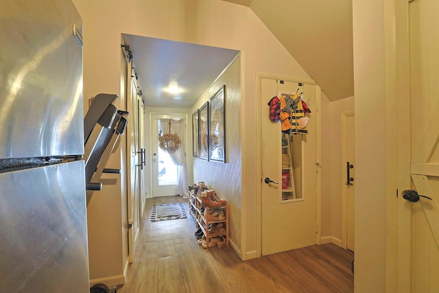 interior space with lofted ceiling, a barn door, and wood finished floors