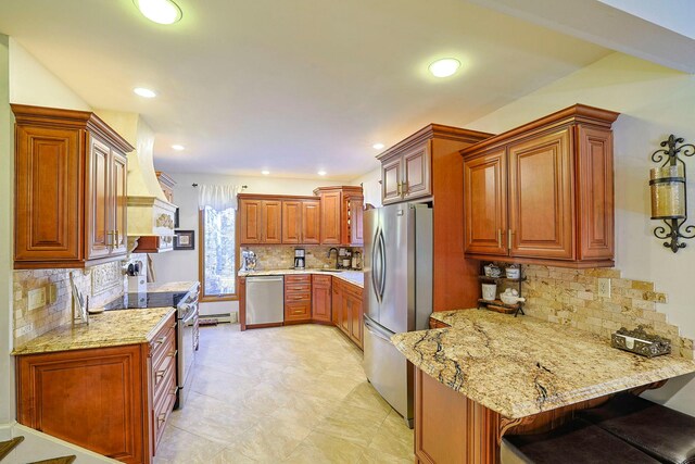 kitchen featuring custom range hood, appliances with stainless steel finishes, brown cabinetry, light stone countertops, and a peninsula