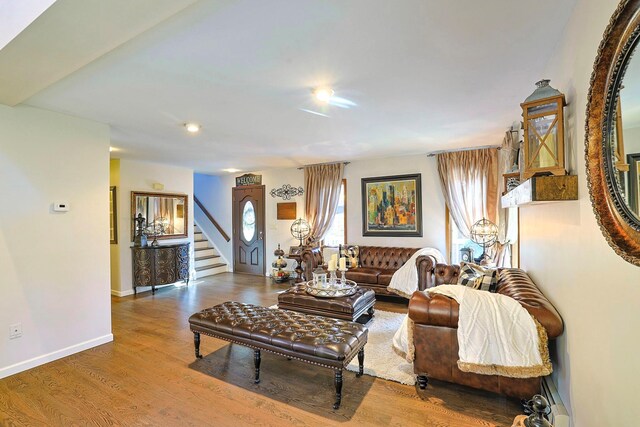 living room featuring baseboards, stairway, and wood finished floors