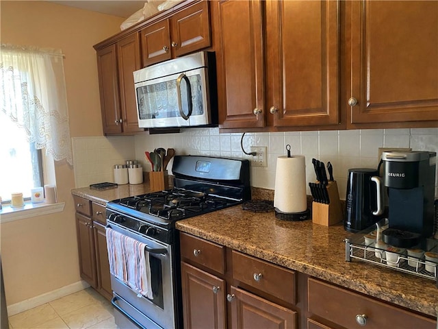 kitchen with dark stone counters, tasteful backsplash, light tile patterned floors, and stainless steel appliances