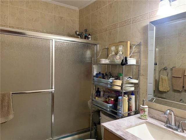 bathroom featuring vanity, ornamental molding, and tile walls