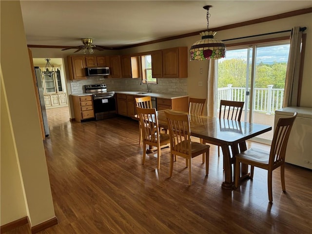 dining room featuring ceiling fan with notable chandelier, dark hardwood / wood-style flooring, ornamental molding, and sink