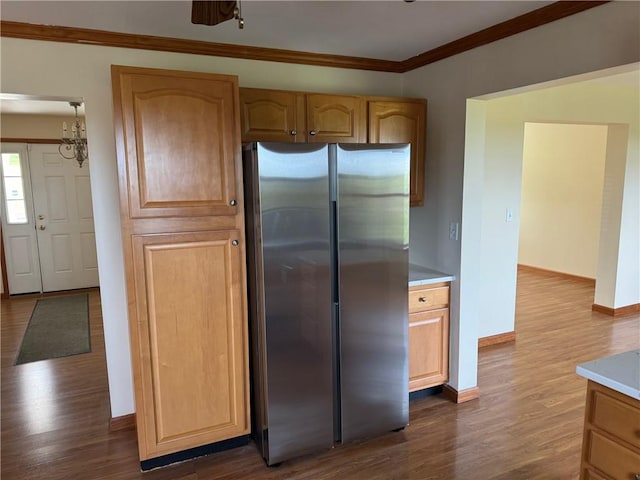 kitchen with stainless steel fridge, ornamental molding, wood-type flooring, and a notable chandelier