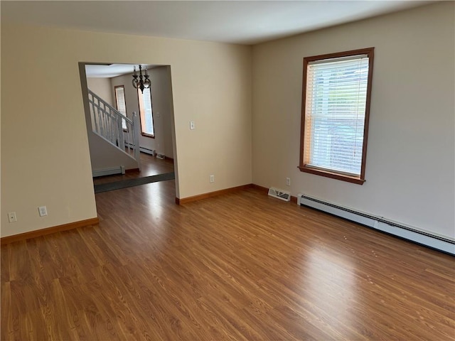 unfurnished room with a chandelier, hardwood / wood-style floors, and baseboard heating