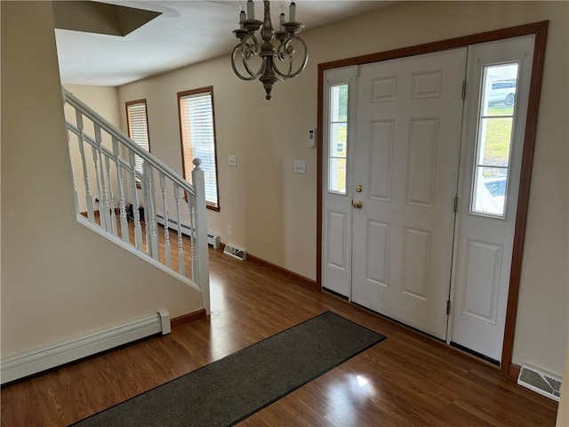 foyer entrance with hardwood / wood-style flooring, a baseboard heating unit, and a notable chandelier