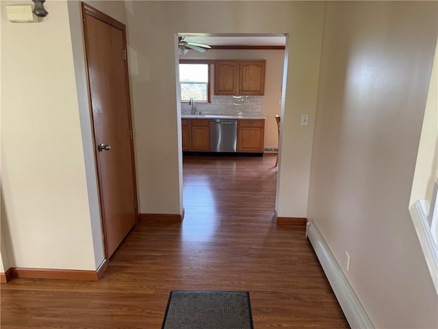 hall featuring baseboard heating, dark wood-type flooring, and sink