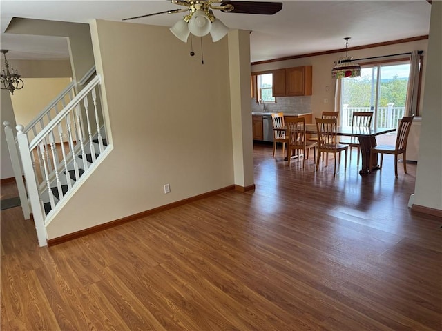 interior space with ornamental molding, ceiling fan with notable chandelier, dark wood-type flooring, and sink